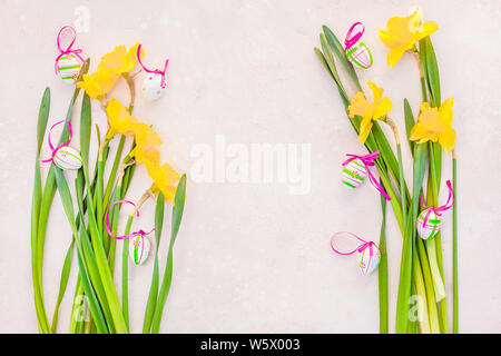 Creative flat lay top view Easter eggs greeting card with yellow daffodils flowers on pink background. Celebration Postcard template Stock Photo