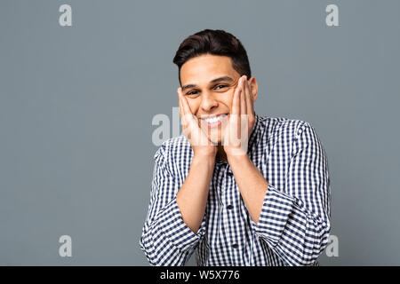 Happy Surprised Man Holding Face In Palms Over Gray Background Stock Photo