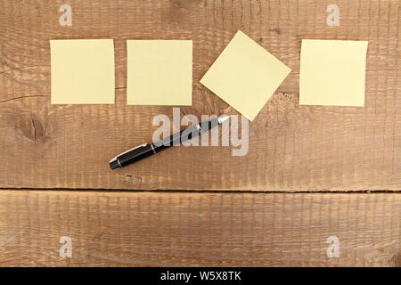 four yellow notes on a wooden table Stock Photo