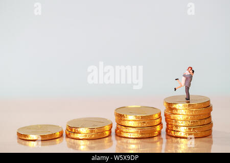 Miniature people: couple standing on stacking golden coins, saving and investment concept using as background Stock Photo