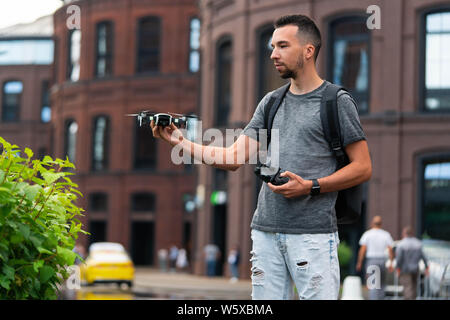 Young handsome man launching drone quadcopter at urban background. cityscape. modern device. Stock Photo
