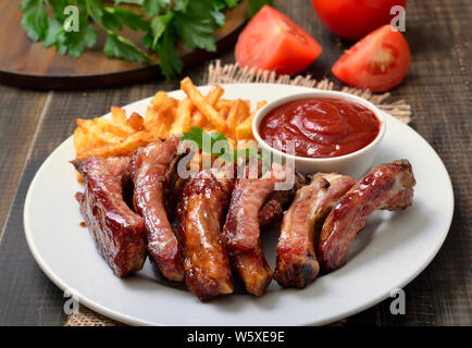 Barbecue pork ribs and vegetables on white plate, close up view Stock Photo