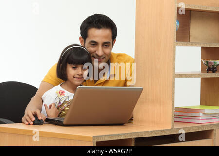Man assisting his daughter in using a laptop Stock Photo