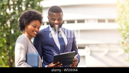 Two african american colleagues discussing new project outdoors Stock Photo
