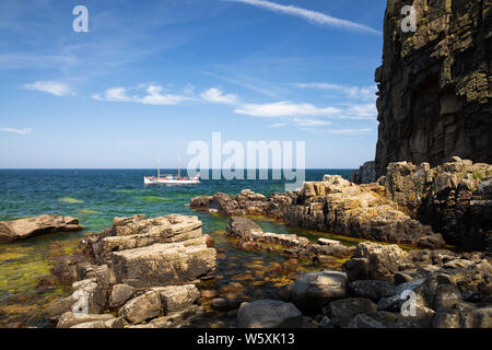 Rugged rock formations of Helligdomsklipperne with tour boat, near Gudhjem, Bornholm, Baltic Sea, Denmark, Europe Stock Photo