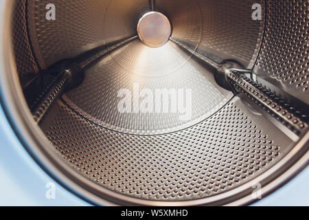 white washing machine door in landromat, with an empty inner drum in blue tint. Stock Photo