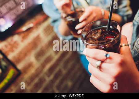 Cocktail glass in woman's hand with bar on back. Stock Photo