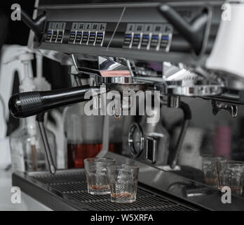 Coffee machine console.Stainless steel stainless steel machine close-up. The handle of the coffee machine is dripping coffee liquid. Transparent glass. Stock Photo
