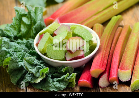 Fresh rhubarb in white bowl on wooden table Stock Photo