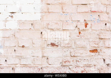 old brick wall with the remains of multi-colored paint Stock Photo