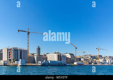 Large construction site including several cranes working on a building complex, with clear blue sky Stock Photo