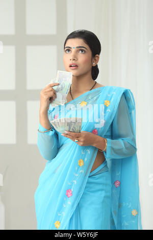 Indian woman showing one hundred rupee banknotes thinking Stock Photo