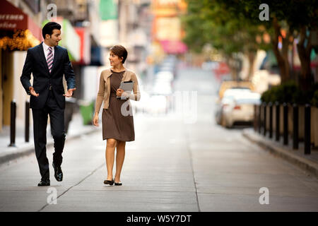 Two business colleagues talking while walking down an urban street. Stock Photo