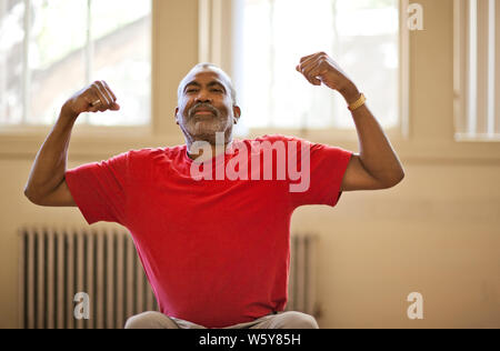 Portrait of a smiling senior man flexing his muscles. Stock Photo