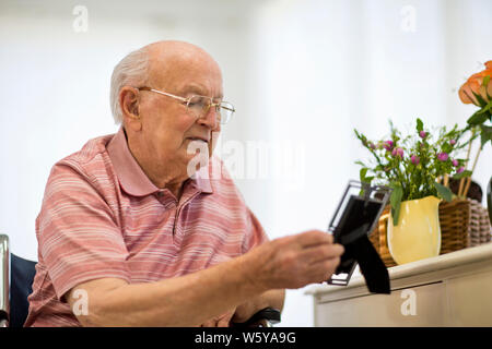 Senior man looking at a picture frame on his bedside table. Stock Photo