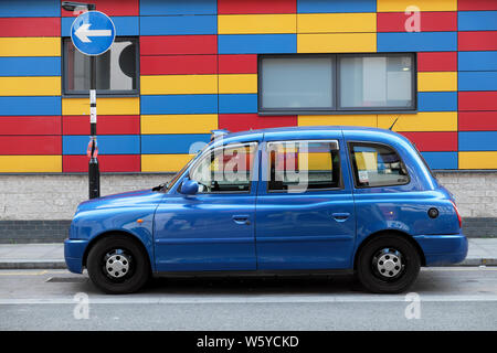 Blue taxi parked outside colourful modern Prior Weston primary school Golden Lane campus building in Whitecross Street London EC1  UK  KATHY DEWITT Stock Photo