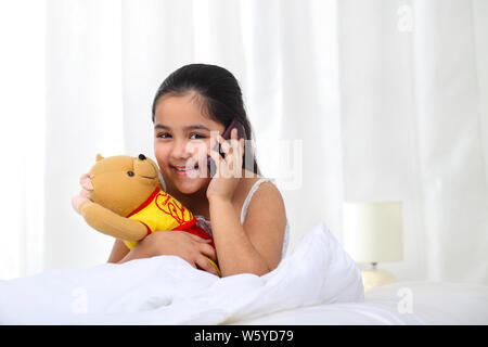 Girl using a mobile phone in the bed and smiling Stock Photo