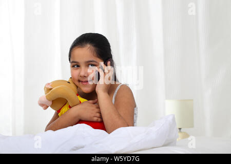 Girl using a mobile phone in the bed Stock Photo