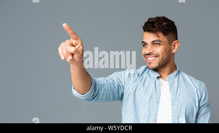 Cheerful Hispanic Man Touching Invisible Screen Interface Stock Photo