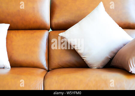 Light color square pillow on the luxury classic vintagae orange brown genuine leather sofa. Stock Photo