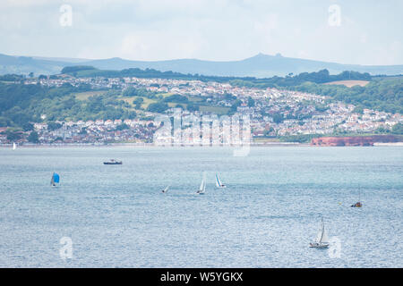 View from Berry Head of sailing boats in front of Preston Sands and Marine Parade on the seafront between Paignton and Torquay, with Haytor visible. Stock Photo