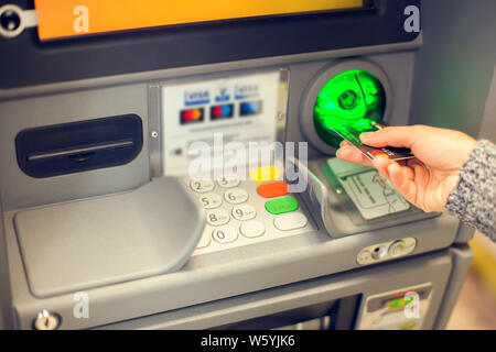 Finance, money, bank and people concept - close up of hand entering pin code at atm machine outdoor Stock Photo