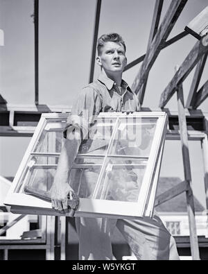 1940s MAN CONSTRUCTION WORKER CARPENTER GLAZIER ON HOUSE BUILDING SITE CARRYING WOOD AND GLASS WINDOW SASHES AND HAMMER - b18736 HAR001 HARS HALF-LENGTH PHYSICAL FITNESS PERSONS RESIDENTIAL MALES BUILDINGS PROFESSION CONFIDENCE B&W FREEDOM SUCCESS SKILL OCCUPATION SKILLS STRENGTH CUSTOMER SERVICE AND REMOVING CAREERS KNOWLEDGE LOW ANGLE PROGRESS PRIDE ON AUTHORITY HOMES OCCUPATIONS CONCEPTUAL PANES RESIDENCE RESPONSIBLE STYLISH SKILLED MID-ADULT MID-ADULT MAN SASH SOLUTIONS TRADESMAN BLACK AND WHITE CAUCASIAN ETHNICITY HAR001 INSTALLING OLD FASHIONED Stock Photo