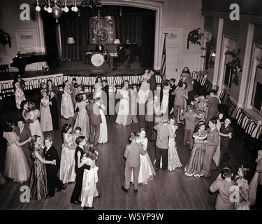 1950s TEENAGE COUPLES GIRLS AND BOYS IN FORMAL DRESSES AND SUITS DANCING AT HIGH SCHOOL SENIOR PROM WITH LIVE BAND IN AUDITORIUM - d2752 LAN001 HARS MAGIC OLD TIME BUSY FUTURE NOSTALGIA BALLROOM OLD FASHION JUVENILE BALANCE SUITS JOY LIFESTYLE CELEBRATION FEMALES HEALTHINESS UNITED STATES COPY SPACE FULL-LENGTH PERSONS UNITED STATES OF AMERICA MALES TEENAGE GIRL TEENAGE BOY ENTERTAINMENT B&W NORTH AMERICA DRESSES NORTH AMERICAN SCHOOLS WIDE ANGLE TEMPTATION SUIT AND TIE DREAMS HAPPINESS HIGH ANGLE AND EXCITEMENT RECREATION AT IN HIGH SCHOOL HIGH SCHOOLS AUDITORIUM CONCEPTUAL AWKWARD STYLISH Stock Photo