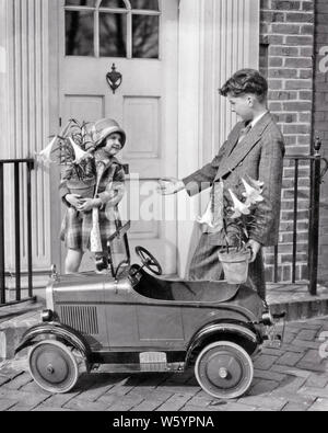 1920s SMALL GIRL AND BOY PUTTING EASTER LILIES INTO TOY CAR  - e70 HAR001 HARS EASTER BROTHERS HOME LIFE COPY SPACE FRIENDSHIP HALF-LENGTH RESIDENTIAL FESTIVAL MALES BUILDINGS CHRISTIAN SIBLINGS SISTERS B&W SUIT AND TIE AND CHRISTIANITY CLOCHE HOMES SIBLING CONNECTION RESIDENCE STYLISH SUNDAY BEST SUPPORT FRONT DOOR DRESSED UP LILIES COOPERATION GROWTH JUVENILES TOGETHERNESS BLACK AND WHITE CAUCASIAN ETHNICITY HAR001 OLD FASHIONED Stock Photo