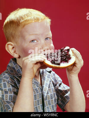 1960s RED HAIRED BOY EATING SLICE OF BREAD WITH GOBS OF JAM HOLDING WITH BOTH HANDS LOOKING AT CAMERA  - kf3717 HAR001 HARS FOODS EYE CONTACT JAM SLICE HUNGRY HAPPINESS HEAD AND SHOULDERS REDHEAD PLEASURE HAIRED RED HAIR YUMMY FAVORITE GROWTH HOLDING ON JUVENILES TASTY BLUE EYES CAUCASIAN ETHNICITY DELICIOUS FRECKLE-FACED HAR001 OLD FASHIONED Stock Photo