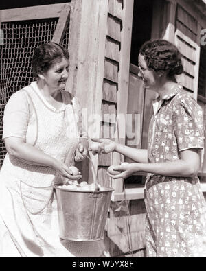 1930s TWO WOMEN FARM WIVES MEETING TALKING OUTSIDE CHICKEN COOP SELECTING EGGS FROM PAIL OF FRESHLY LAID EGGS - p2832 HAR001 HARS COPY SPACE FRIENDSHIP HALF-LENGTH LADIES PERSONS UNITED STATES OF AMERICA FARMING CONFIDENCE GOSSIPING AGRICULTURE B&W NORTH AMERICA BRUNETTE DRESSES NORTH AMERICAN FRESH SELLING PAIL CHOICE EXTERIOR FARMERS COOP OF OCCUPATIONS CONNECTION FRIENDLY FRESHLY COOPERATION MID-ADULT MID-ADULT WOMAN POULTRY TOGETHERNESS WIVES BLACK AND WHITE CAUCASIAN ETHNICITY HAR001 LAID OLD FASHIONED SELECTING Stock Photo