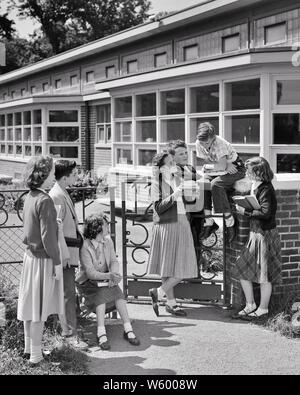 1950s GROUP OF PRETEEN JUNIOR HIGH SCHOOL STUDENTS IN FRONT OF SCHOOL BUILDING SHARING BOOKS TALKING HANGING OUT - s2836 HAR001 HARS FULL-LENGTH HALF-LENGTH MALES BUILDINGS B&W SKIRTS FREEDOM HAPPINESS HIGH ANGLE STYLES CHOICE KNOWLEDGE SEVEN HANGING OUT OF PRETEEN SWEATERS CONNECTION STRUCTURES 7 STYLISH IN FRONT OF JUNIOR AFTER SCHOOL FASHIONS GROWTH JUVENILES MIDDLE SCHOOL PRE-TEEN PRE-TEEN BOY PRE-TEEN GIRL RELAXATION TOGETHERNESS BLACK AND WHITE CAUCASIAN ETHNICITY HAR001 OLD FASHIONED Stock Photo