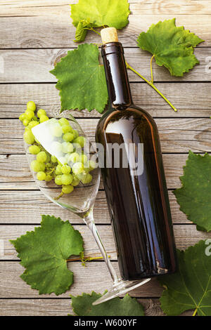 Bottle of wine with a glass and grapes on a wooden table, top view Stock Photo