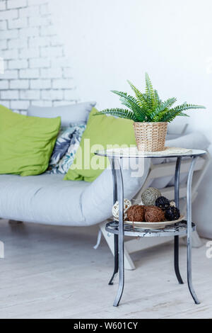 Living room with grey sofa, decorative green pillows and plant.Stylish Interior of room in eco style with soft couch and green plant in pot.Copy space Stock Photo
