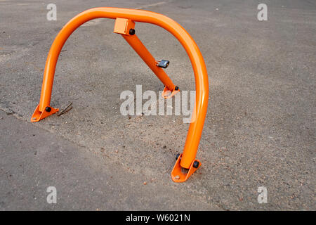 orange road parking barrier mounted on asphalt Stock Photo