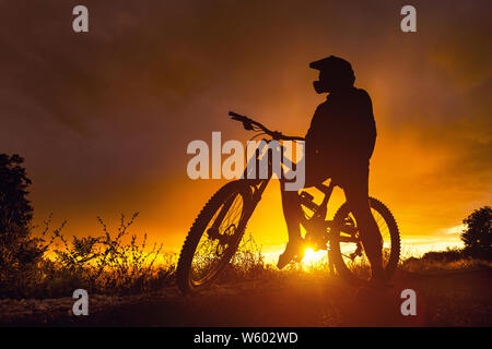 Downhill mountain bike rider silhouette at sunset with full face helmet Stock Photo Alamy