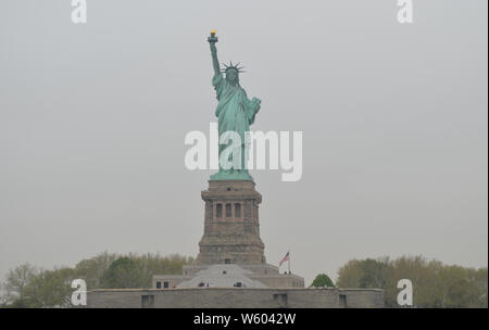 Spring in New York City: Statue of Liberty (American Flag to the right) on an Overcast Morning Stock Photo