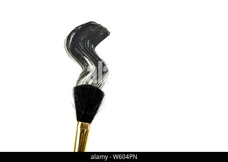 Flat lay view of black charcoal mud mask line smeared with makeup brush isolated on white for background use. Facial skin care. Stock Photo