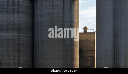 Silos made of solid concrete and a chimney standing in the sunshine Stock Photo