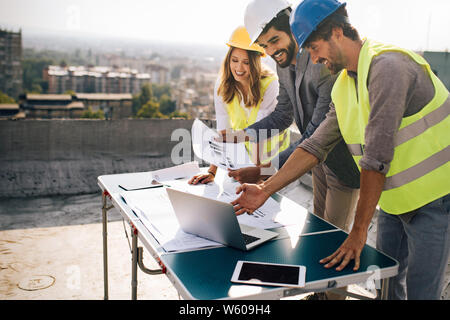 Architects team and engineers looking paper plans at construction site. Stock Photo
