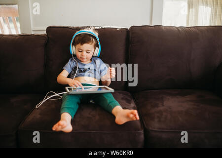 Young boy happily using tablet to play educational games at home Stock Photo