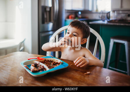 Young boy eating ribs while sitting at dining room table Stock Photo