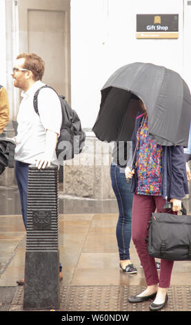 London, UK. 30th July, 2019. Woman with an umbrella enclosed to the sides to keep dry in the London rain. Credit: Joe Kuis: Alamy / News Stock Photo