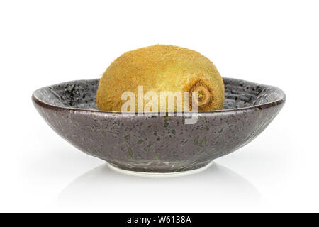 One whole fresh green kiwifruit actinidia deliciosa in a dark ceramic bowl isolated on white background Stock Photo