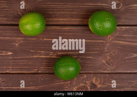 Group of three whole fresh green lime flatlay on brown wood Stock Photo