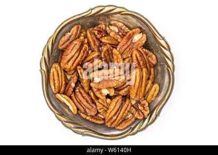 Lot of whole fresh brown pecan nut half in old iron bowl flatlay isolated on white background Stock Photo