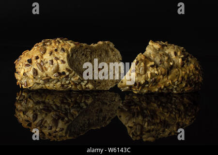Group of two halves of fresh cereal baguette one sliced isolated on black glass Stock Photo
