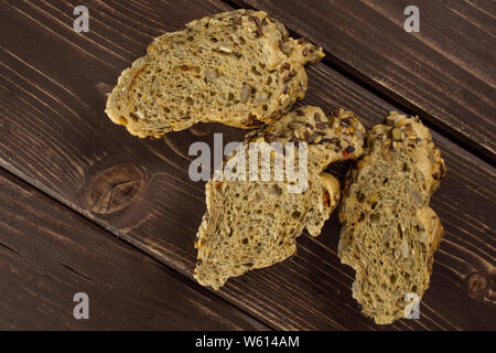 Group of three slices of fresh cereal baguette flatlay on brown wood Stock Photo