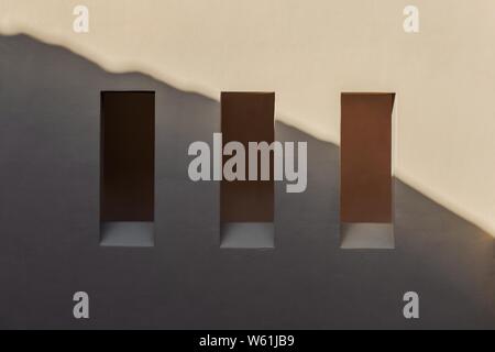 Beautiful shot of a white wall with three vertical rectangular window holes and a shadow Stock Photo