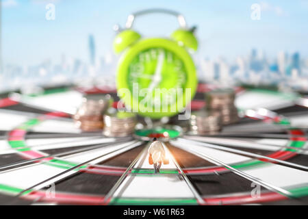 Miniature people: businessman running on dart board and try to race against time and beat the clock to be a winner Stock Photo